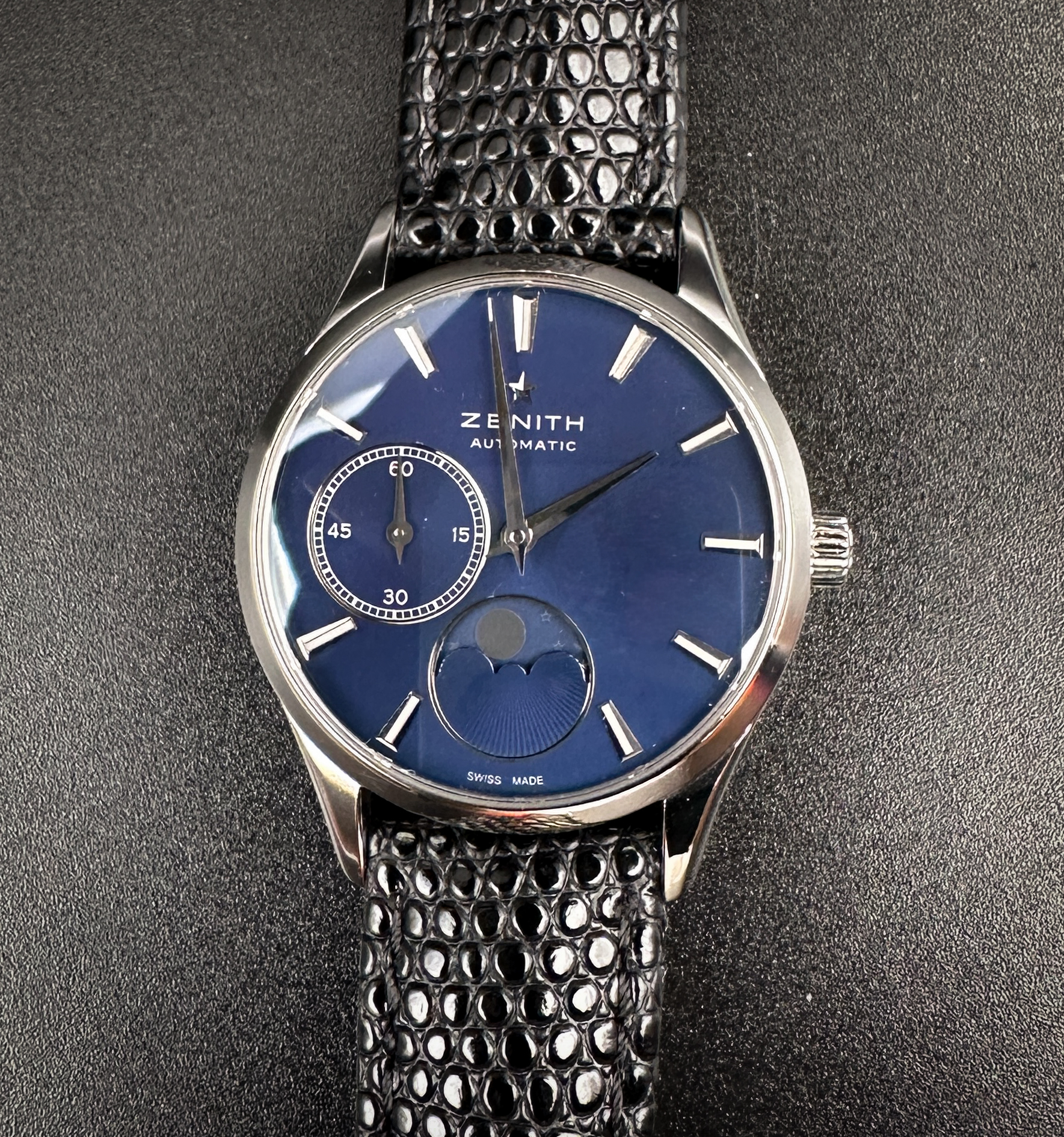 Zenith Ultra-Thin Moonphase Elite 03-23110.692 in a 33mm stainless steel case, featuring the Zenith Elite automatic movement. This Zenith has been tested in excellent working order and is ready to wear. Includes a new Wrist Wraith watch roll; Original Zenith Buckle; and TLC Warranty/Authentication card. Case Serial Number: 1285XX