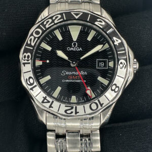 1998 Omega Seamaster 300 GMT 50th Anniversary in a 41mm stainless steel case, featuring the Omega caliber 1128 automatic movement. This Omega has been tested in excellent working order and is ready for wear or to be added to a collection. The 1128 Hour wheel was replaced in September 2025, a common point of failure for the Seamaster GMT. Includes: Outer box, inner wooden case, instructions book, leatherette wallet, and TLC warranty/authentication card.
