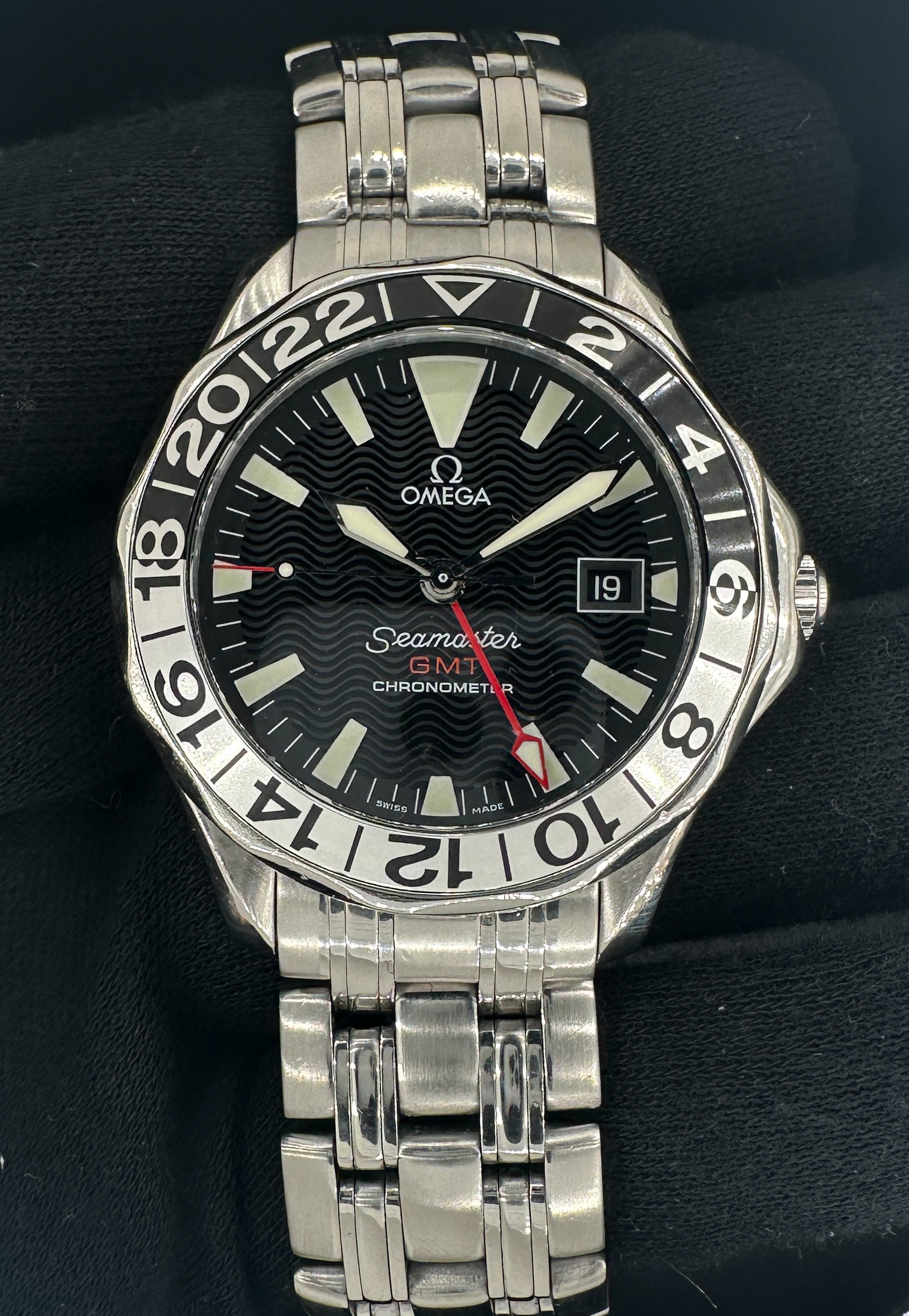 1998 Omega Seamaster 300 GMT 50th Anniversary in a 41mm stainless steel case, featuring the Omega caliber 1128 automatic movement. This Omega has been tested in excellent working order and is ready for wear or to be added to a collection. The 1128 Hour wheel was replaced in September 2025, a common point of failure for the Seamaster GMT. Includes: Outer box, inner wooden case, instructions book, leatherette wallet, and TLC warranty/authentication card.