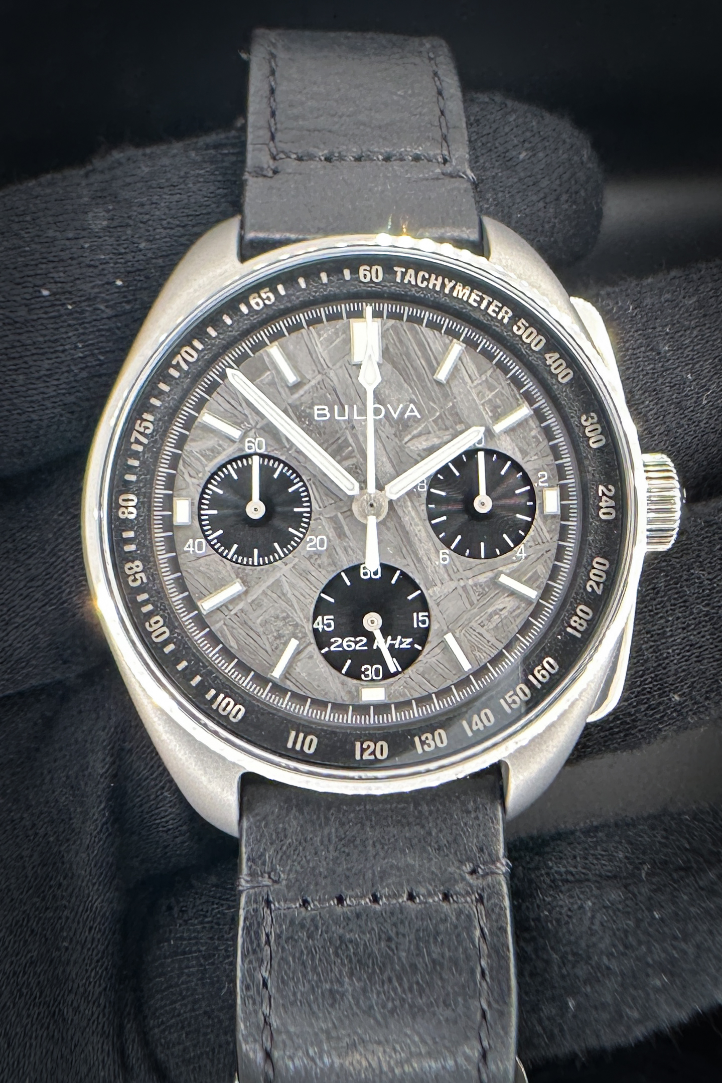 Bulova Lunar Pilot Meteorite Dial 96A312 Limited Edition #3364/5000. This Bulova includes: outer box, inner case, booklet, certificate of authenticity, and open warranty card. On August 2, 1971, Bulova made space history: during the Apollo 15 moon landing, one of the astronauts wore the first Lunar Pilot. The new special edition has a unique dial made of meteorite rock and is limited to 5,000 pieces. The Lunar Pilot Chronograph features a 43.5 mm sandblasted silver-colored grade 5 titanium case with polished accents. Beneath the flat sapphire crystal, the six-hand chronograph dial is carefully crafted from genuine Muonionalusta meteorite. This 4.5 billion year old meteorite was discovered in northern Scandinavia in 1906 and its varied crystal pattern makes each dial unique. The Lunar Pilot is powered by Bulova's proprietary high-precision quartz movement, which oscillates at a frequency of 262 kHz for unparalleled accuracy and features a sweeping chronograph hand. The watch is fitted with a matching black leather strap that features an easy-release system for quick changes. This edition is limited to 5,000 pieces.