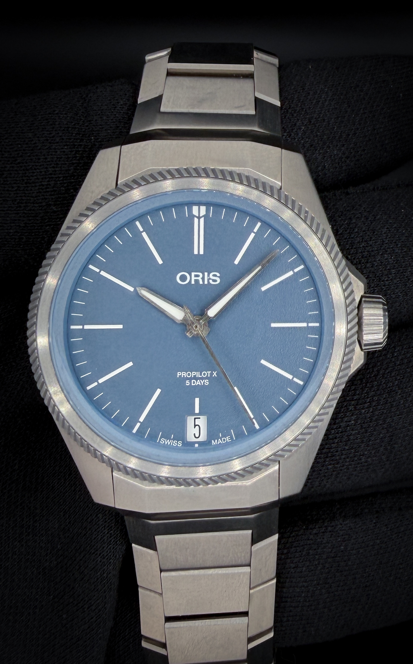 The Oris ProPilot X Calibre 400 Ref. 01 400 7778 7155, is a contemporary expression of independent Swiss watchmaking, combining cutting-edge movement technology with lightweight, aerospace-inspired design. Crafted entirely from titanium, both the case and integrated bracelet offer exceptional strength while remaining remarkably light and comfortable on the wrist. The case measures 39mm in diameter, approximately 11.8mm in thickness, and features a lug-to-lug of about 47mm—making it an ideal size for daily wear. The signature turbine-style bezel, textured dial, and sapphire crystal with anti-reflective coating complete the modern, technical aesthetic.