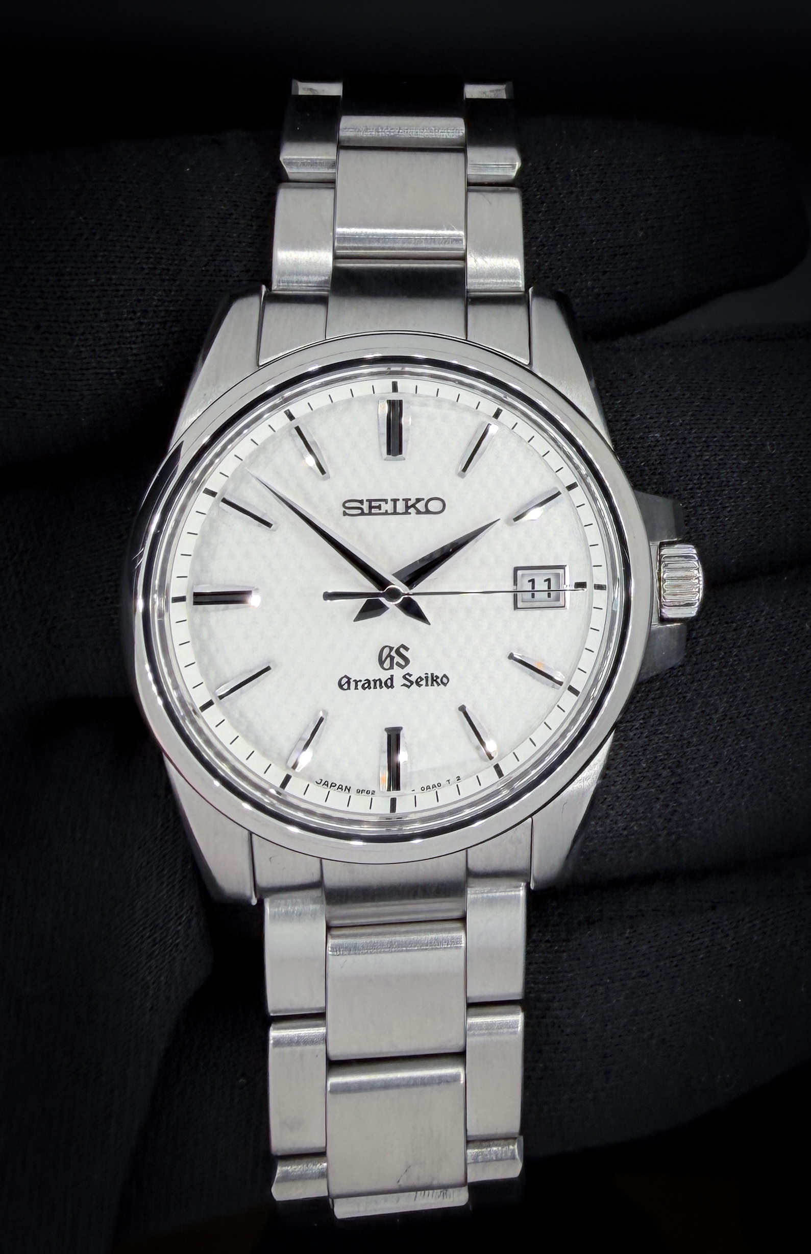 The Grand Seiko Heritage Collection SBGX253 is a masterclass in restrained precision and everyday refinement. This example features the crisp white dial variant, offering a clean, highly legible aesthetic that perfectly showcases Grand Seiko’s razor-sharp, Zaratsu-polished hands and faceted hour markers. Light plays beautifully across the dial and indices, delivering the signature brilliance and depth collectors expect from the brand. The 37mm stainless steel case measures approximately 10mm thick, giving it an ideal, versatile presence on the wrist—substantial yet refined. The solid-link stainless steel bracelet provides a balanced feel and excellent comfort for daily wear.