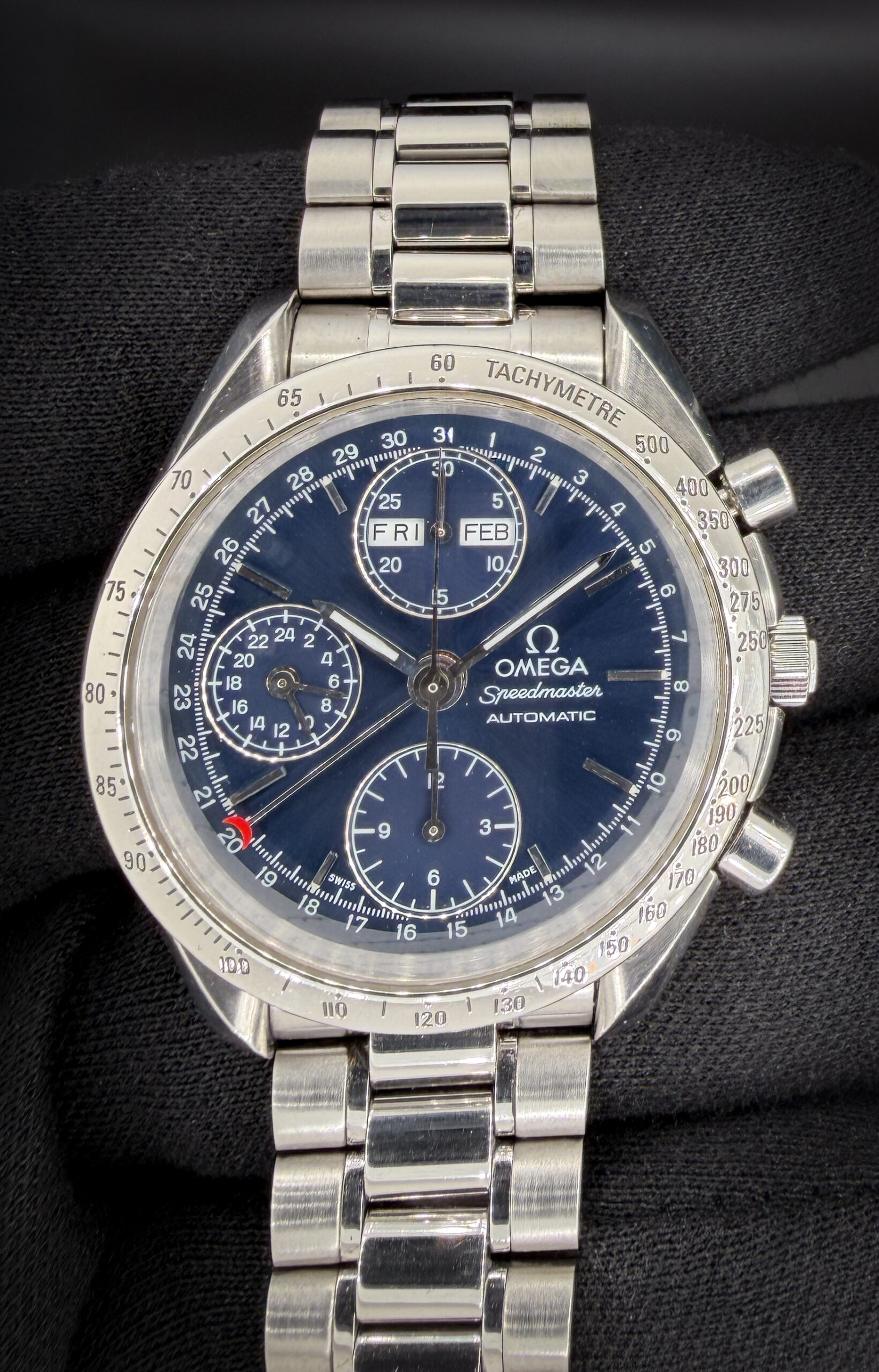 Vintage c. 1998 Omega Speedmaster Day-Date Triple Calendar 3521.80 in a 39mm stainless steel case, featuring the Omega caliber 1151 automatic movement. This Speedmaster was serviced January 2026 and includes an Omega white cardboard box; Wood Case; Omega Travel Box; and TLC Warranty/Authentication card. Accuracy Testing: +2 SPD / 279Amplitude / .2ms Beat Error Caseback Serial Number: 55985XX