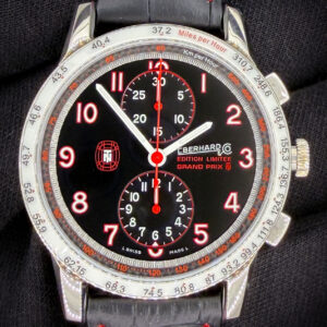 Offered here is the Eberhard & Co. Tazio Nuvolari Grand Prix Chronograph Limited Edition, limited to 999 pieces, reference 31061.1, presented in new condition. This model celebrates Eberhard’s longstanding connection to historic motorsport as the Official Timekeeper of the Gran Premio Nuvolari, an international rally honoring one of the most legendary racing drivers of all time, Tazio Nuvolari. The watch features a bold and distinctive design, highlighted by a white "MPH" bezel with red and black markers that complement the black dial with red accents. The stainless steel case measures approximately 43mm, offering a strong and sporty wrist presence. It is powered by the reliable ETA Valjoux 7750 automatic chronograph movement, delivering a power reserve of approximately 42 hours. The watch is fitted on a black leather strap with red stitching and also includes an additional black strap for versatility. This example includes the outer box, inner case, guaranty booklet, and open warranty cards dated 14 JUIL 2021.