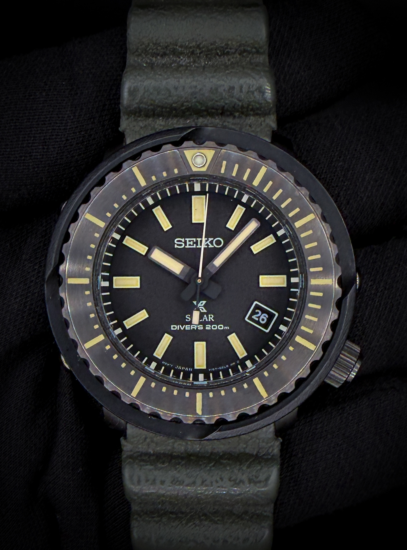 Seiko Prospex “Tuna” Street Series Solar Diver, reference SNE543P1, in a 47mm case, a modern reinterpretation of Seiko’s iconic shrouded dive watch design. This model features a bold, stealth-inspired aesthetic with a matte black dial, high-contrast luminous markers, and the signature protective outer shroud that defines the legendary “Tuna” lineup. The compact case design wears comfortably while maintaining the rugged, tool-watch presence Prospex divers are known for. This example includes the original outer box, inner case, instruction booklet, and hang tag. The watch is fitted on the factory green silicone strap, offering a distinctive look while maintaining durability and comfort for daily wear or active use.