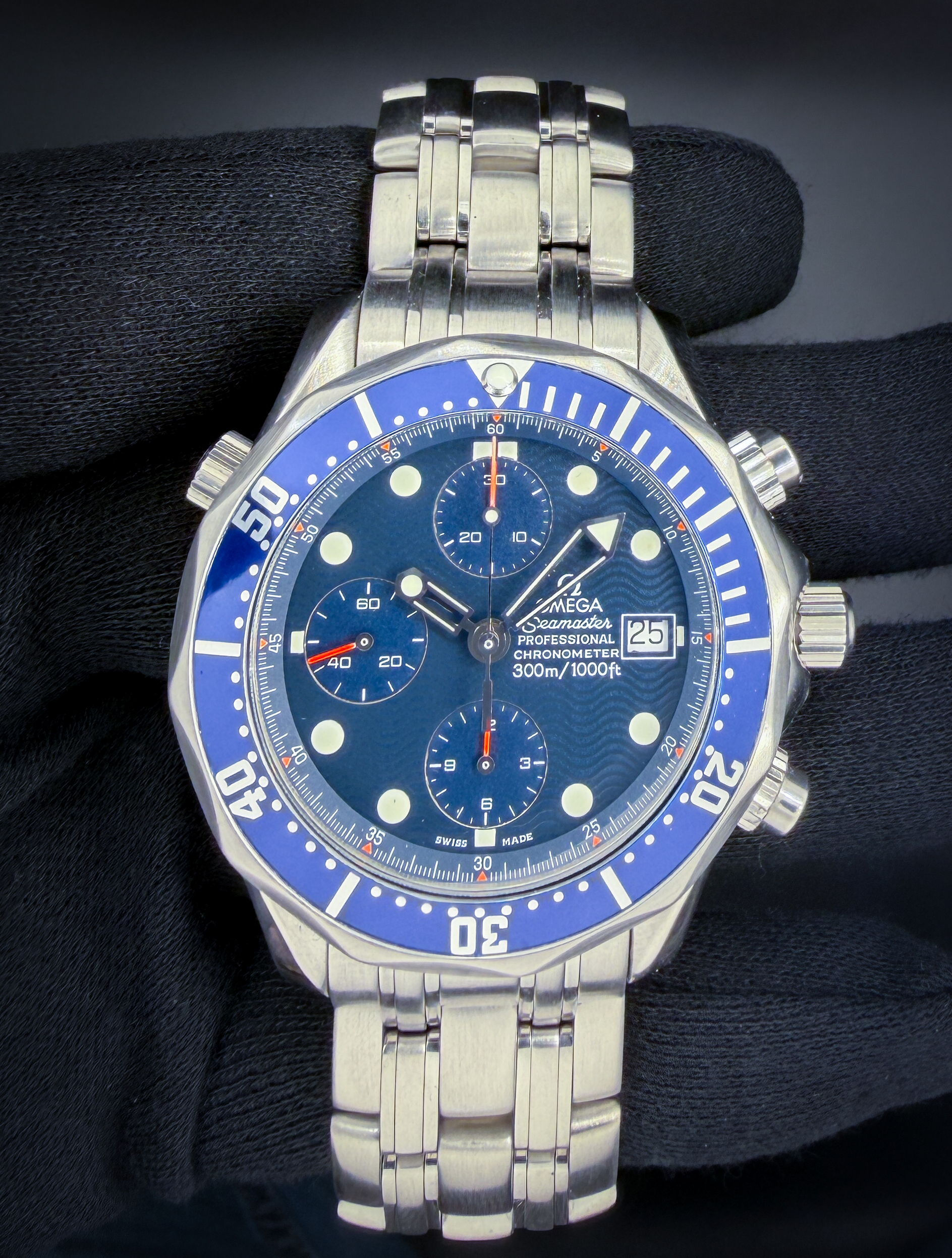 Offered here is the Omega Seamaster 300 Chronograph reference 2599.80.00, circa 2000, featuring the iconic blue wave dial with luminous sword hands, applied hour markers, and matching blue bezel. The stainless steel case measures approximately 42mm and is powered by the Omega caliber 1164 automatic chronograph movement, delivering reliable performance in a robust, tool-oriented platform. This reference represents a classic era of Seamaster design, blending professional dive watch capability with everyday versatility. Case Serial Number: 60027XXX