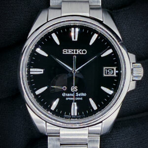 Offered here is a Grand Seiko Heritage Spring Drive Date, reference SBGA027, housed in a 39mm stainless steel case and showcasing the brand’s renowned balance of precision engineering and refined finishing. The black dial offers exceptional legibility with applied indices, a framed date window, and a power reserve indicator, all complemented by Grand Seiko’s signature smooth sweeping seconds hand. Powered by the Spring Drive Caliber 9R65, this model delivers outstanding accuracy with the unique glide motion that defines Grand Seiko’s hybrid technology. This example includes: the outer box, inner presentation case, rice paper cover, card booklet, instruction booklet, and Spring Drive handbook. Specifications Serial Number: 910XXX Condition:This example presents in very strong overall condition, with light, honest wear consistent with careful use. The watch retains excellent case geometry and finishing throughout.