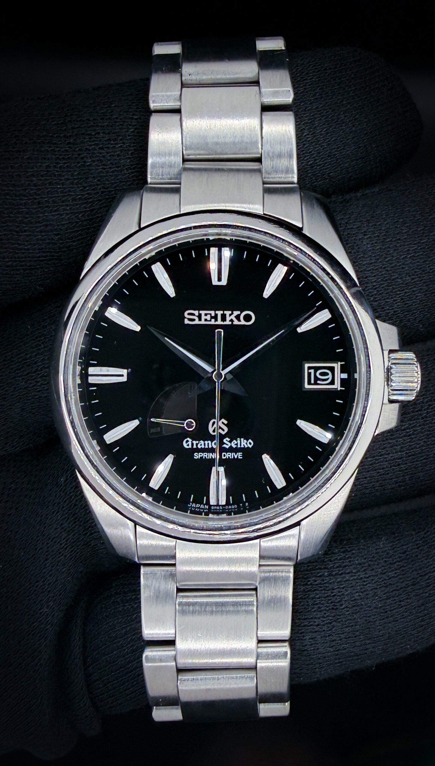 Offered here is a Grand Seiko Heritage Spring Drive Date, reference SBGA027, housed in a 39mm stainless steel case and showcasing the brand’s renowned balance of precision engineering and refined finishing. The black dial offers exceptional legibility with applied indices, a framed date window, and a power reserve indicator, all complemented by Grand Seiko’s signature smooth sweeping seconds hand. Powered by the Spring Drive Caliber 9R65, this model delivers outstanding accuracy with the unique glide motion that defines Grand Seiko’s hybrid technology. This example includes: the outer box, inner presentation case, rice paper cover, card booklet, instruction booklet, and Spring Drive handbook. Specifications Serial Number: 910XXX Condition:This example presents in very strong overall condition, with light, honest wear consistent with careful use. The watch retains excellent case geometry and finishing throughout.