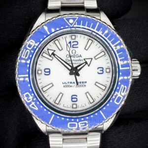 Omega Seamaster Planet Ocean Ultra Deep 216.30.46.21.04.001 in a 45.5mm stainless steel case, powered by the Omega caliber 8912 Master Chronometer movement. This reference represents Omega’s most extreme production dive watch, derived directly from the record-setting Ultra Deep prototypes that reached the Challenger Deep. This example features the highly desirable white dial configuration with bold blue Arabic numerals and matching blue ceramic bezel, creating a striking and highly legible contrast. The dial is clean and crisp, with broad arrow hands and applied indices filled with luminous material for excellent underwater visibility.