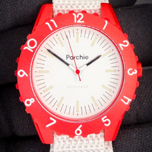 Limited Edition Parchie Lunar-Time 36mm PARCHIE-HOD-36-RED. This like-new watch includes the original Watches of Switzerland box; purchase card; and Parchie box with insert. True to Parchie’s brightly-colored roots, the Parchie Lunar-Time Limited Editions for Hodinkee feature a bold metallic red aluminum case reminiscent of a certain iconic case specifically designed for the intensity of space travel. The red bezel is home to white numerals designed to easily reference the black-tipped hour and minute hands for little learners. The creamy white dial includes black hash marks and a faux lume treatment on the indices, and a jolt of red on the second hand perfectly matches the case - a stellar combination if you ask us. And if you look closely, you’ll even spot the Hodinkee logo hidden at six o’clock.