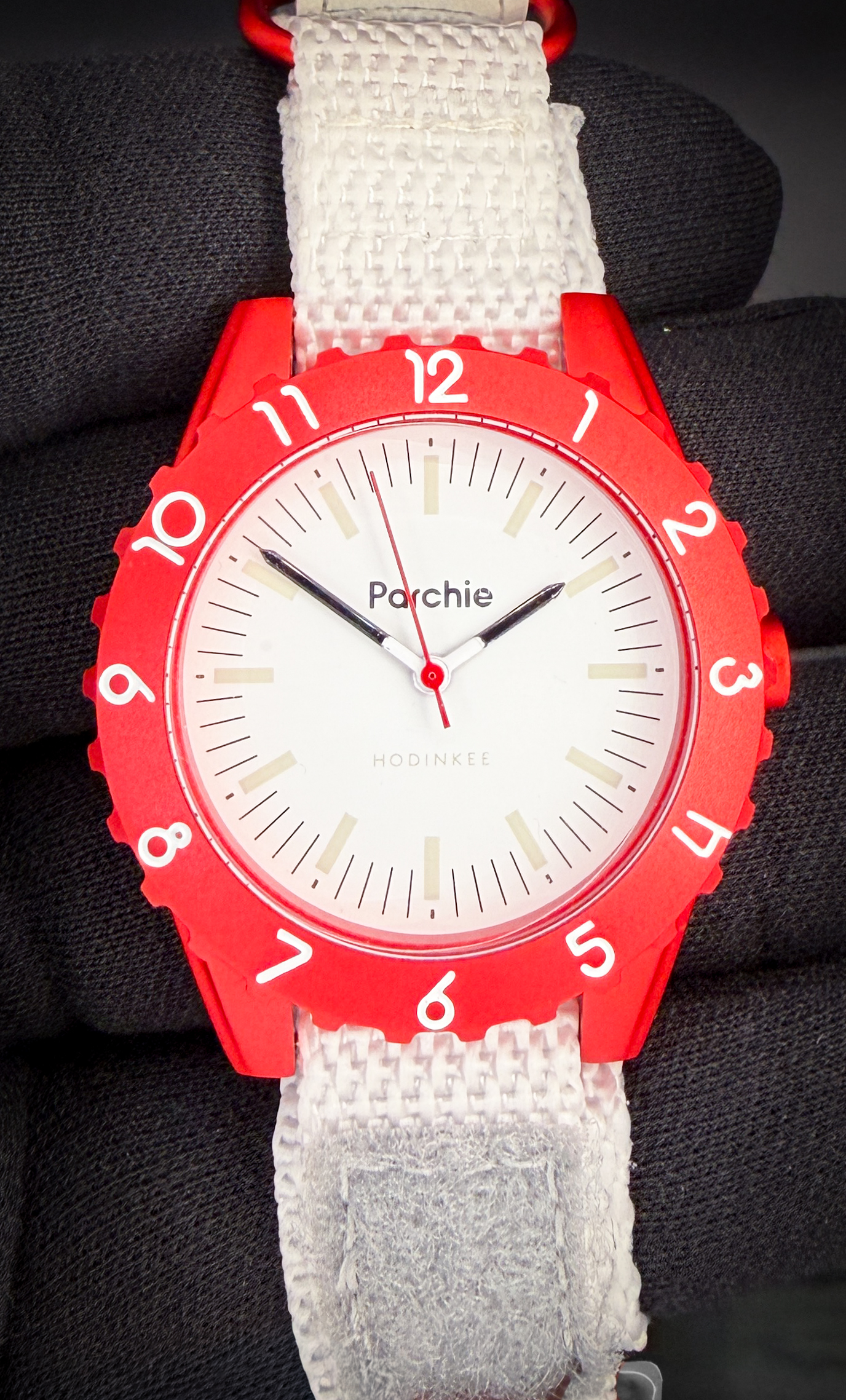 Limited Edition Parchie Lunar-Time 36mm PARCHIE-HOD-36-RED. This like-new watch includes the original Watches of Switzerland box; purchase card; and Parchie box with insert.  True to Parchie’s brightly-colored roots, the Parchie Lunar-Time Limited Editions for Hodinkee feature a bold metallic red aluminum case reminiscent of a certain iconic case specifically designed for the intensity of space travel. The red bezel is home to white numerals designed to easily reference the black-tipped hour and minute hands for little learners. The creamy white dial includes black hash marks and a faux lume treatment on the indices, and a jolt of red on the second hand perfectly matches the case - a stellar combination if you ask us. And if you look closely, you’ll even spot the Hodinkee logo hidden at six o’clock.