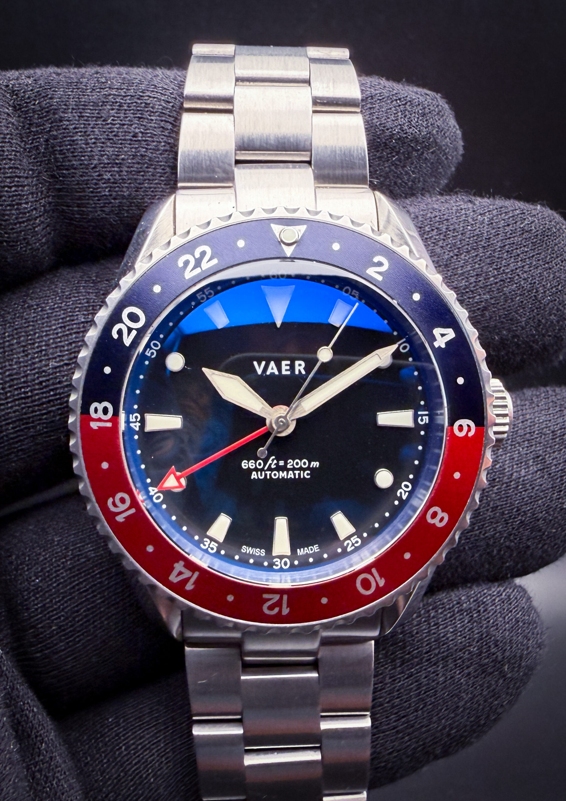 VAER G7 Meridian Pepsi VA-G7-01 in a stainless steel case, featuring the classic blue-and-red “Pepsi” GMT bezel configuration that pays direct homage to the iconic mid-century travel watches pioneered by Rolex’s legendary GMT-Master references. Designed as VAER’s modern interpretation of the traditional dual-time sports watch, the G7 Meridian blends vintage airline-era styling with contemporary everyday durability, including a clean matte dial, highly legible luminous markers, and an integrated GMT hand for tracking a second time zone. The watch is powered by the Swiss Sellita SW330-2 automatic GMT movement, offering true mechanical traveler functionality with proven reliability and smooth operation. Paired with a versatile stainless steel bracelet and balanced proportions, the G7 Meridian Pepsi captures the spirit of classic aviation tool watches while delivering an approachable modern alternative inspired by one of the most recognizable GMT designs ever created.