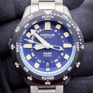 Nodus Sector Deep Pioneer-Admiral NO-DPA-01 in a stainless steel case measuring approximately 38mm in diameter, blending compact vintage dive-watch proportions with modern tool-watch engineering and finishing. The Deep Pioneer Admiral draws strong inspiration from classic skin divers and military-issued dive watches of the 1950s and 1960s — particularly the restrained symmetry and functional simplicity seen in early Tudor and Blancpain dive references — while incorporating Nodus’ distinctly modern approach to case finishing, bracelet integration, and daily wear ergonomics. The deep blue “Admiral” dial is paired with a matching timing bezel and oversized luminous markers for excellent legibility, while the overall design captures the spirit of vintage underwater exploration without becoming a direct homage piece. Powering the watch is the Japanese-made Seiko NH35 automatic movement, chosen for its reliability, hacking capability, and ease of long-term serviceability. With its slim wearable dimensions, solid bracelet construction, and vintage-inspired aesthetic, the Nodus Deep Pioneer Admiral offers a refined modern interpretation of the classic mid-century dive watch formula.