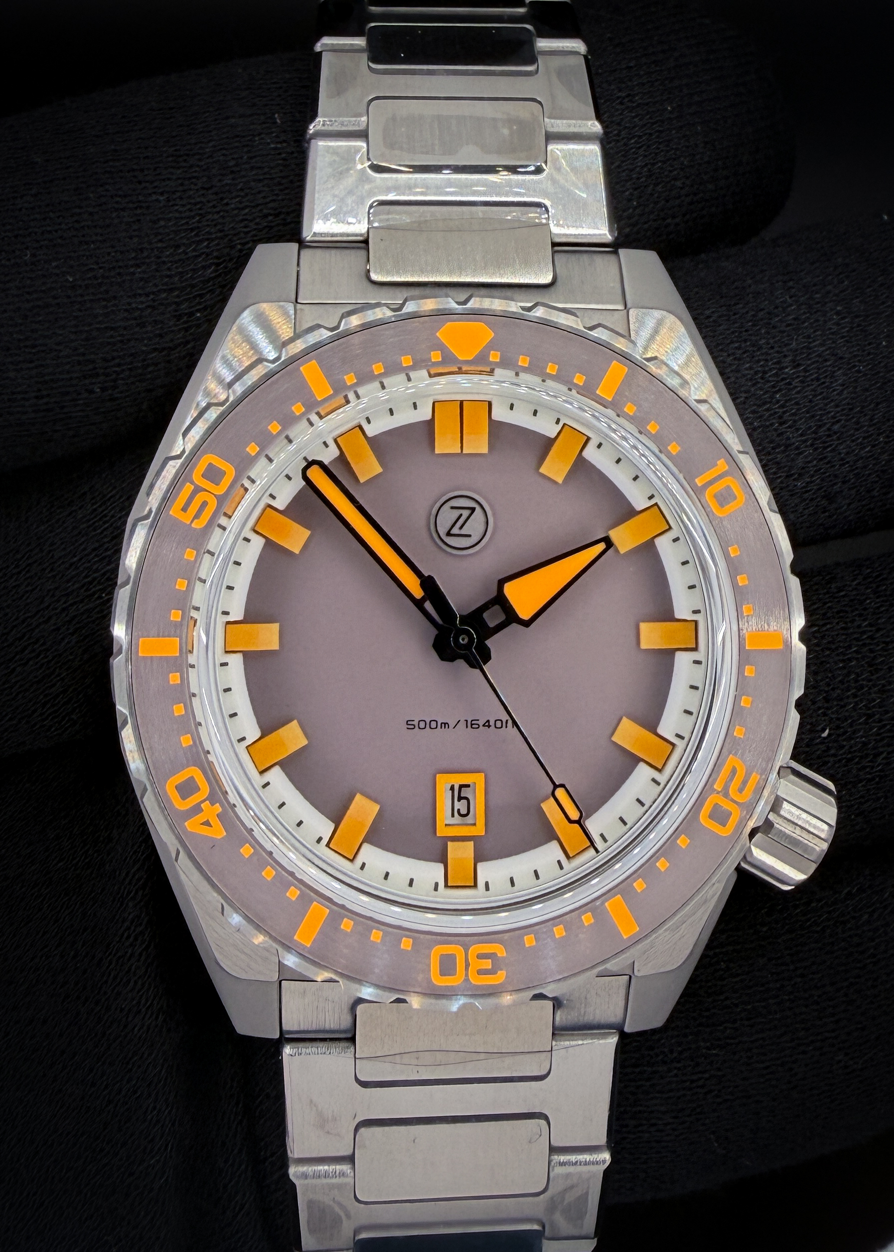 Zelos Thresher 44mm “Ember” – Limited Edition #144/150 The Zelos Thresher “Ember” pairs a matte, sandblasted grey dial with vivid orange Lumicast hour markers and bold luminous hands. Its 44mm stainless steel case features a grey ceramic bezel with orange markings, a domed sapphire crystal with an internal anti-reflective coating, and a screw-down crown. Powered by the Miyota 9015 automatic movement, it offers a date display at six o’clock and a factory water-resistance rating of 500 meters. A 120-click unidirectional bezel and stainless steel bracelet with a quick-adjust clasp complete this distinctive dive watch.